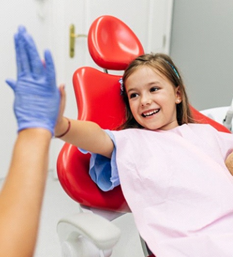 Young girl high-fives her Garland pediatric dentist