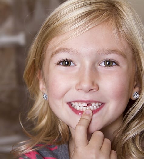 Little girl pointing to gap left by extracted tooth