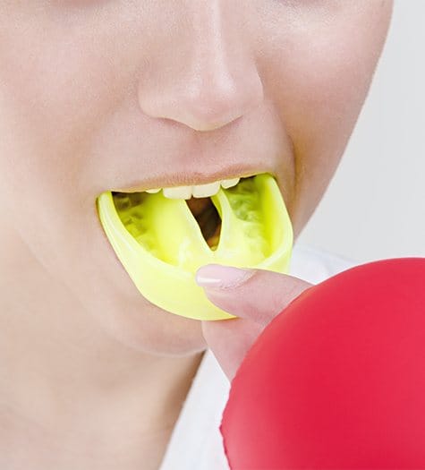 Teen girl placing bright green athletic mouthguard