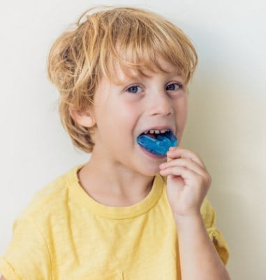 Child placing athletic mouthguard